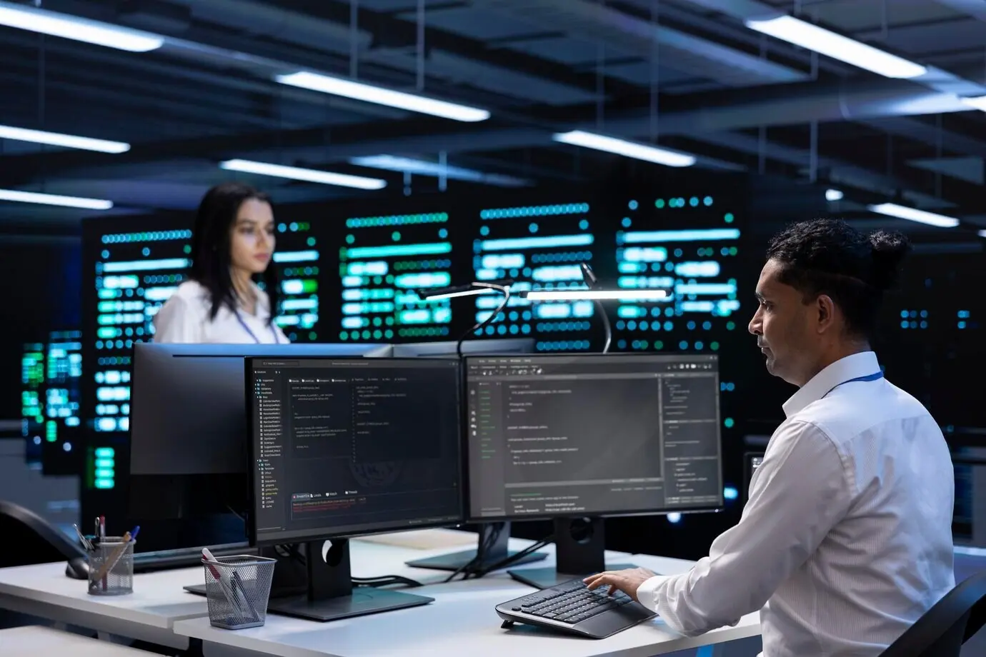 Colleagues in a data center using computers to identify firewall misconfigurations.